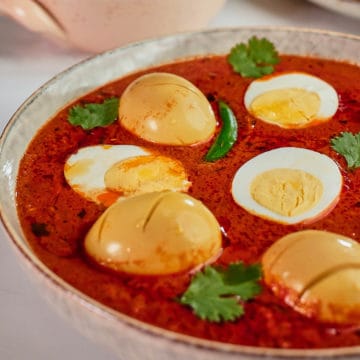 Close up view of eggs in tomato curry served in a bowl.