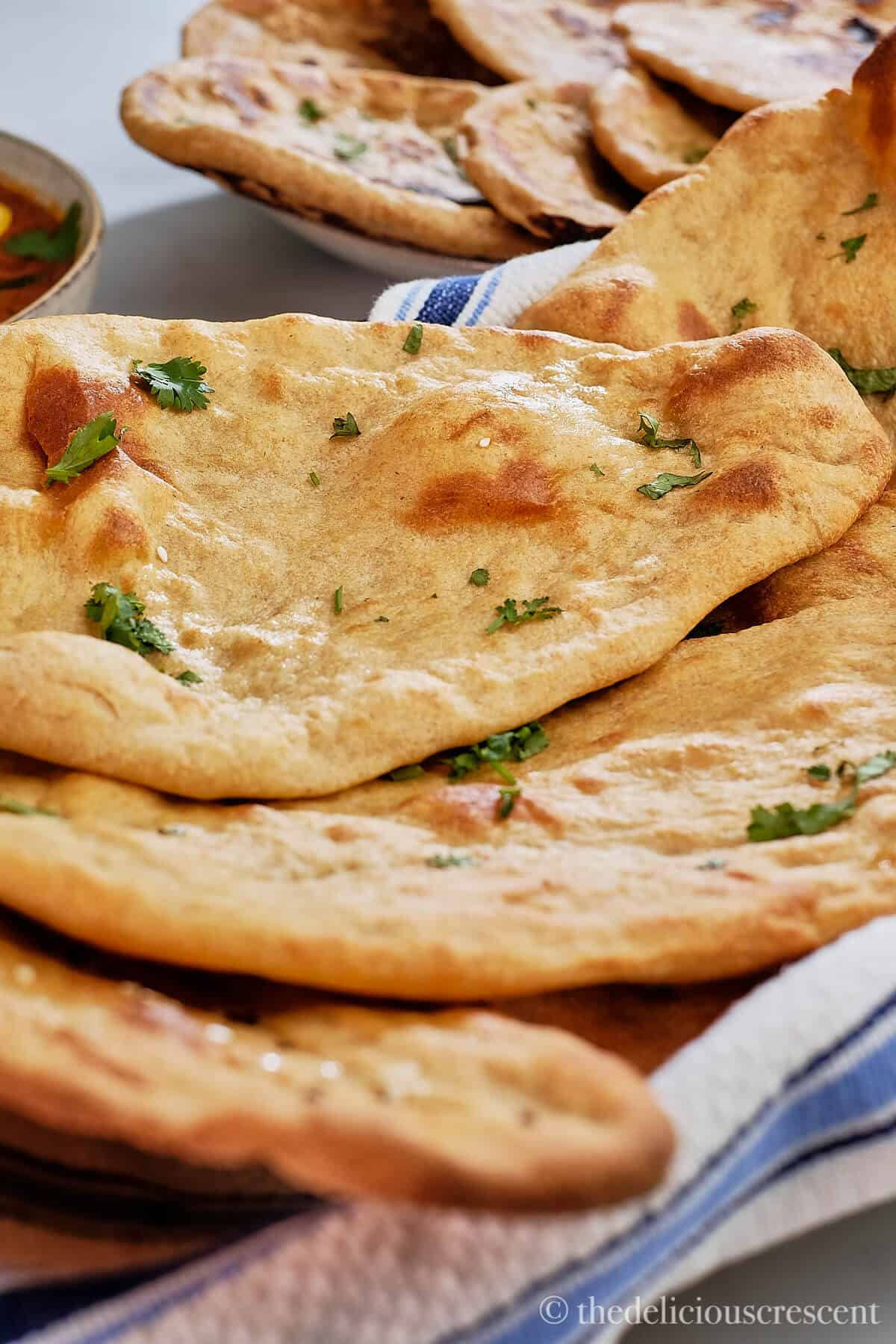 A stack of whole grain naans in a basket.