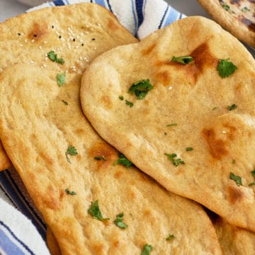 Close up view of whole wheat naans on a kitchen towel.