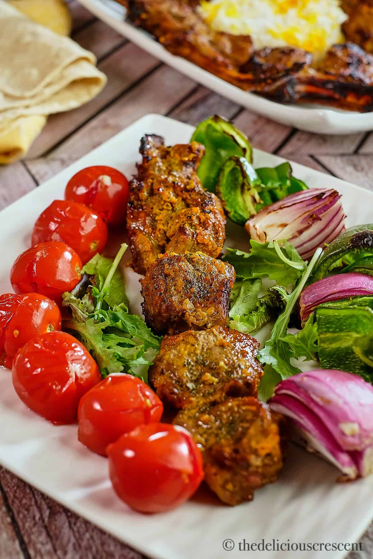 Lamb with grilled vegetables on a plate.