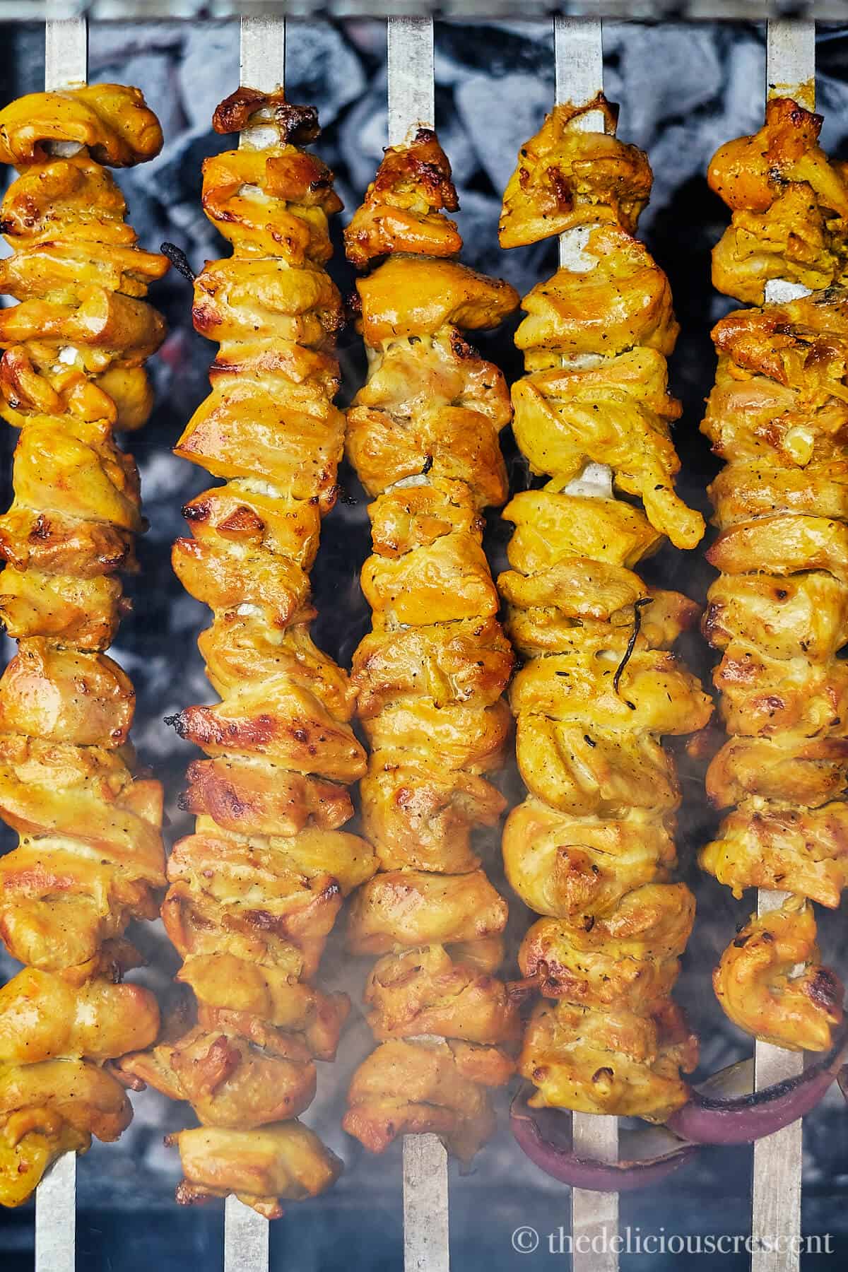 Chicken grilling on skewers.