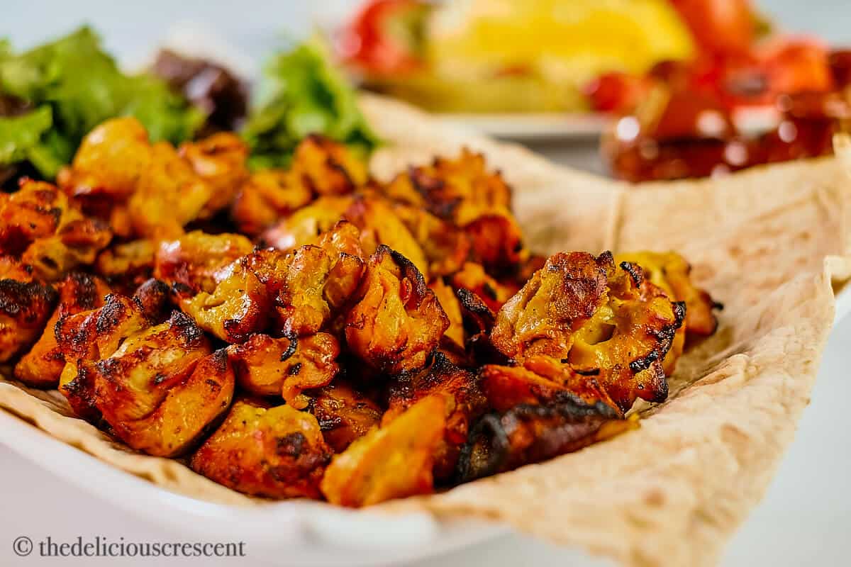 Persian chicken kebabs served on a flatbread in a plate.