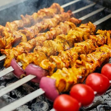 Close up view of Persian grilled chicken kabobs on skewers.