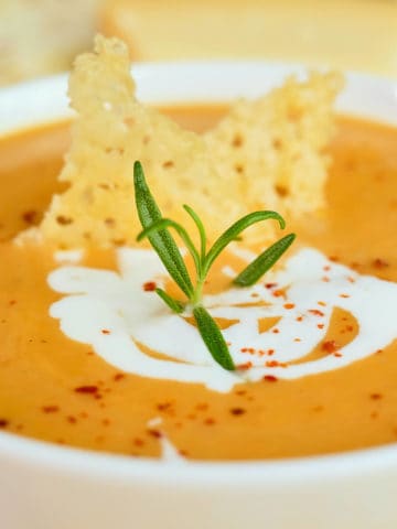 Close up view of sweet potato soup made with coconut milk and topped with parmesan crisps.
