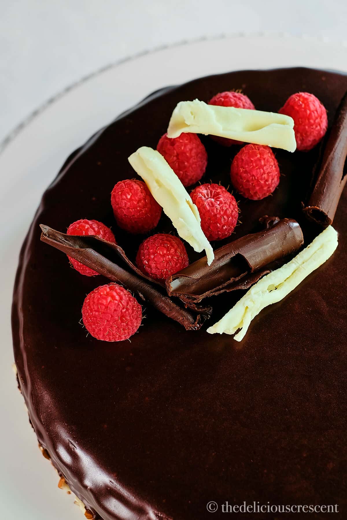 Top view of chocolate almond cake with fresh raspberries and chocolate curls.