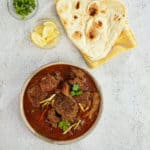 Close up view of beef nihari with naan bread.