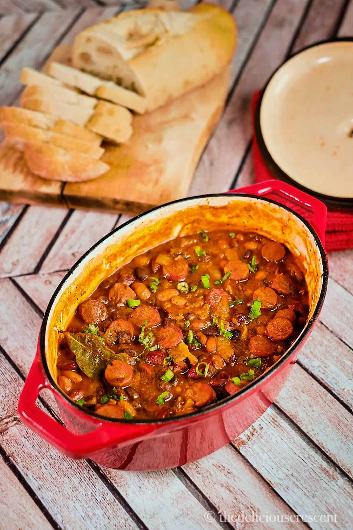 Bean stew cooked with sausage and served in a dutch oven.