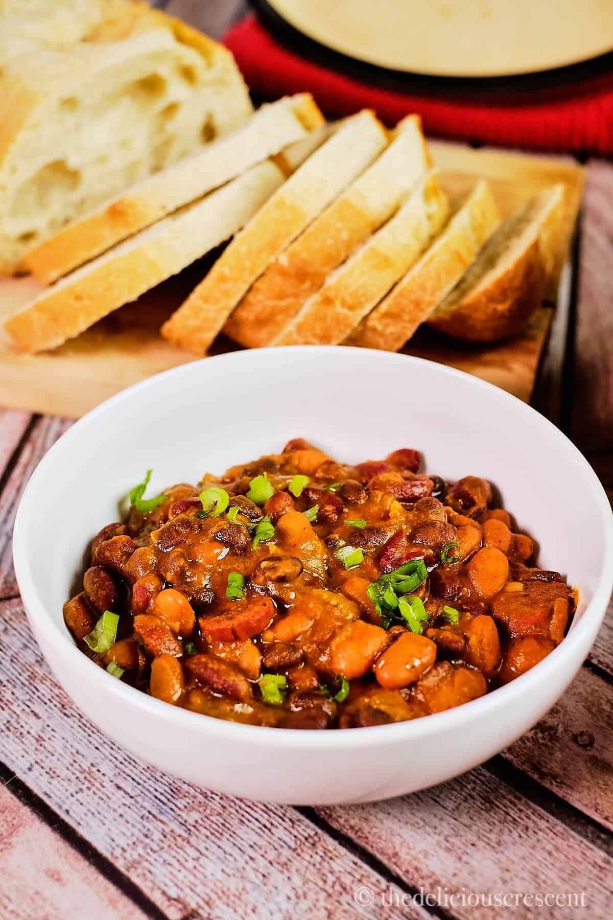 A bowl of bean and sausage stew served with bread.