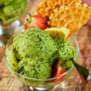 Close up view of matcha ice cream with wafers and fruit.