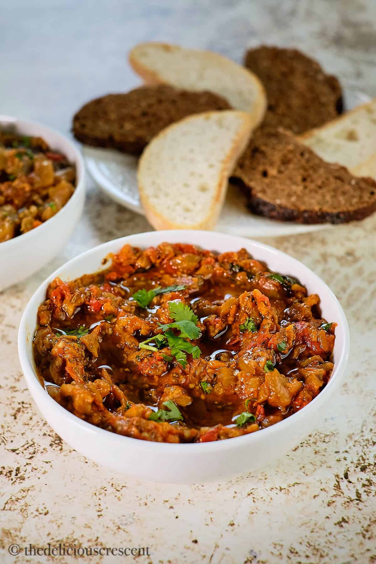 Zaalouk served in a white bowl along with crusty bread.