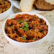 Close up view of zaalouk served in a white bowl along with crusty bread.