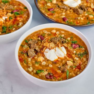 Close up view of beef and barley soup prepared in Persian style and served in bowls.