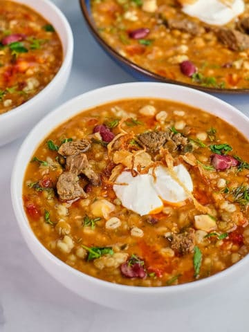 Close up view of beef and barley soup prepared in Persian style and served in bowls.