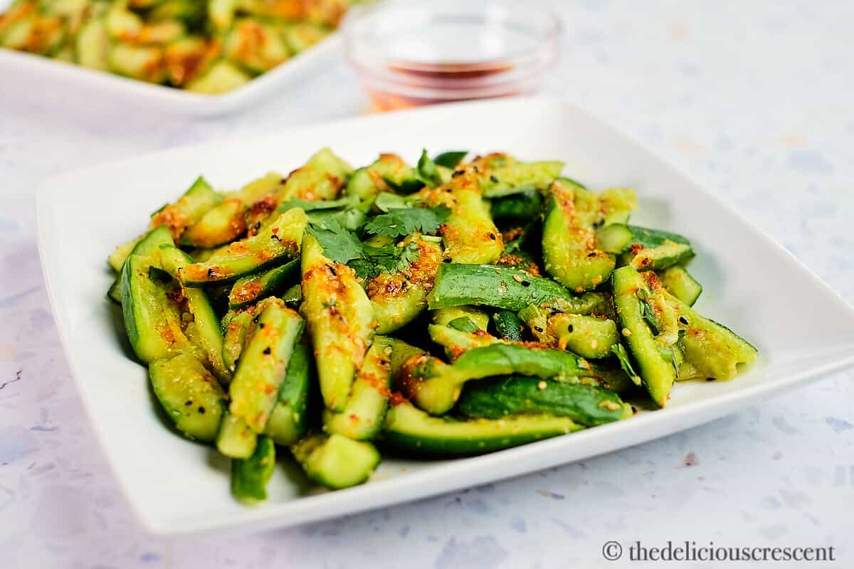 Smashed salad made with cucumbers and spices on a plate.