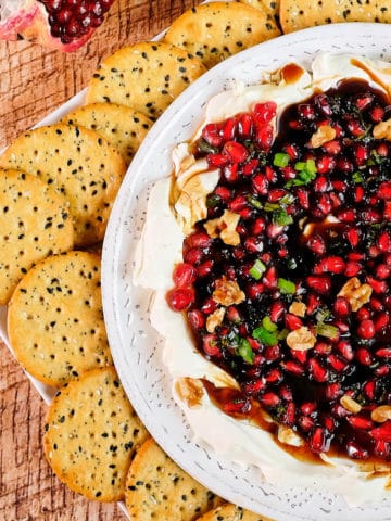 Close up view of salsa dip served with cream cheese and crackers.