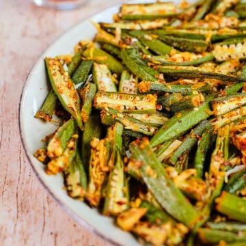 Close up view of roasted okra seasoned with spices and served on a plate.