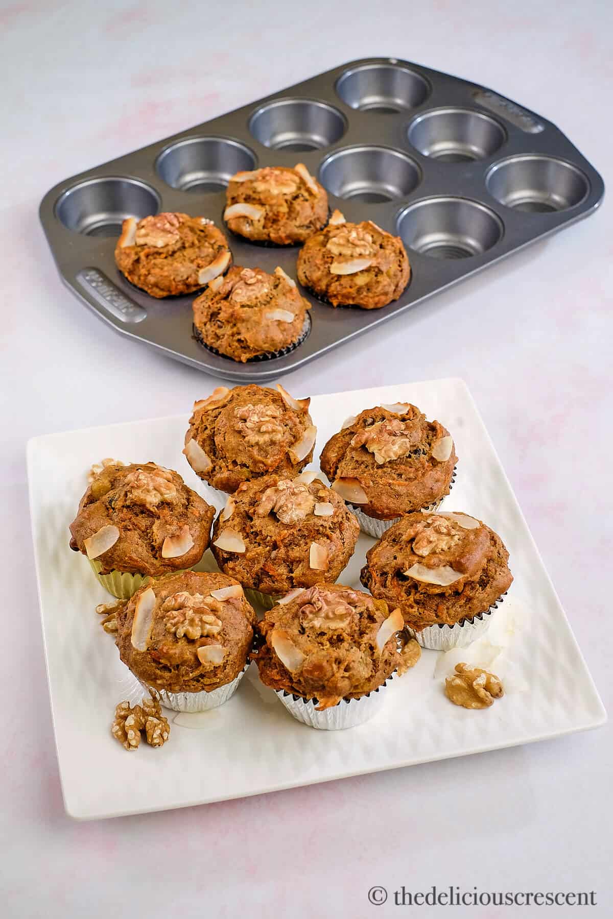 Several healthy carrot muffins placed on a white plate.