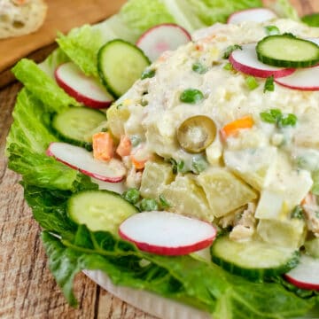 Close up view of salad olivieh made with chicken and potatoes served in a plate.