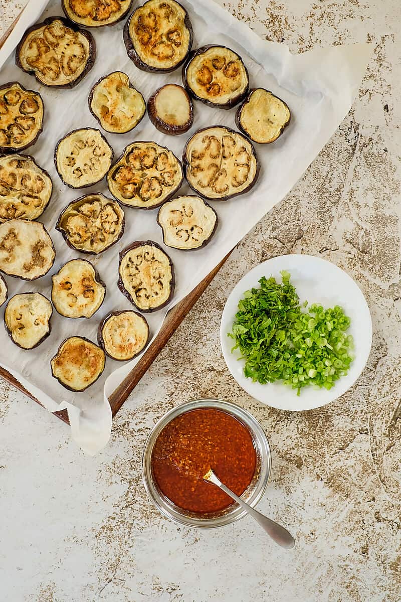 Roasted eggplant, herbs and Asian style sauce on a table.