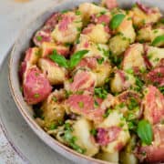 Close up view of vegan German potato salad in a grey bowl.