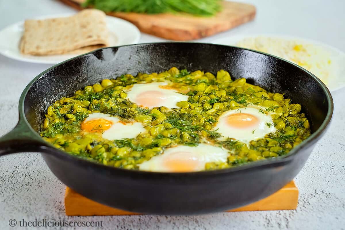Eggs stewed with beans and dill in a skillet.