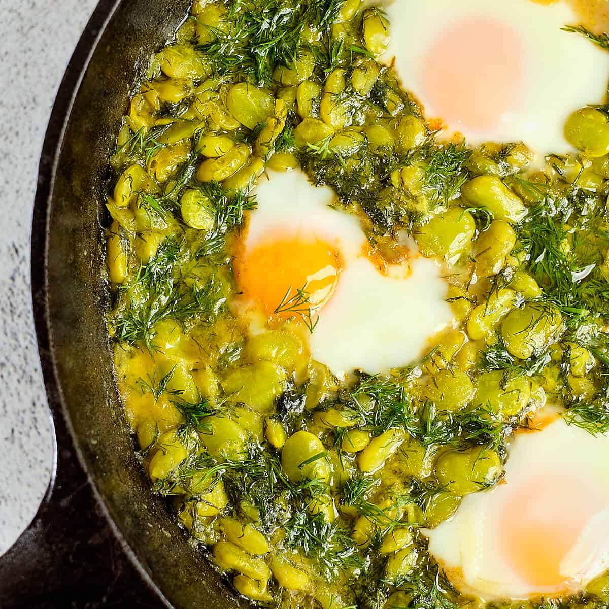 Close view of beans and eggs cooked with dill.