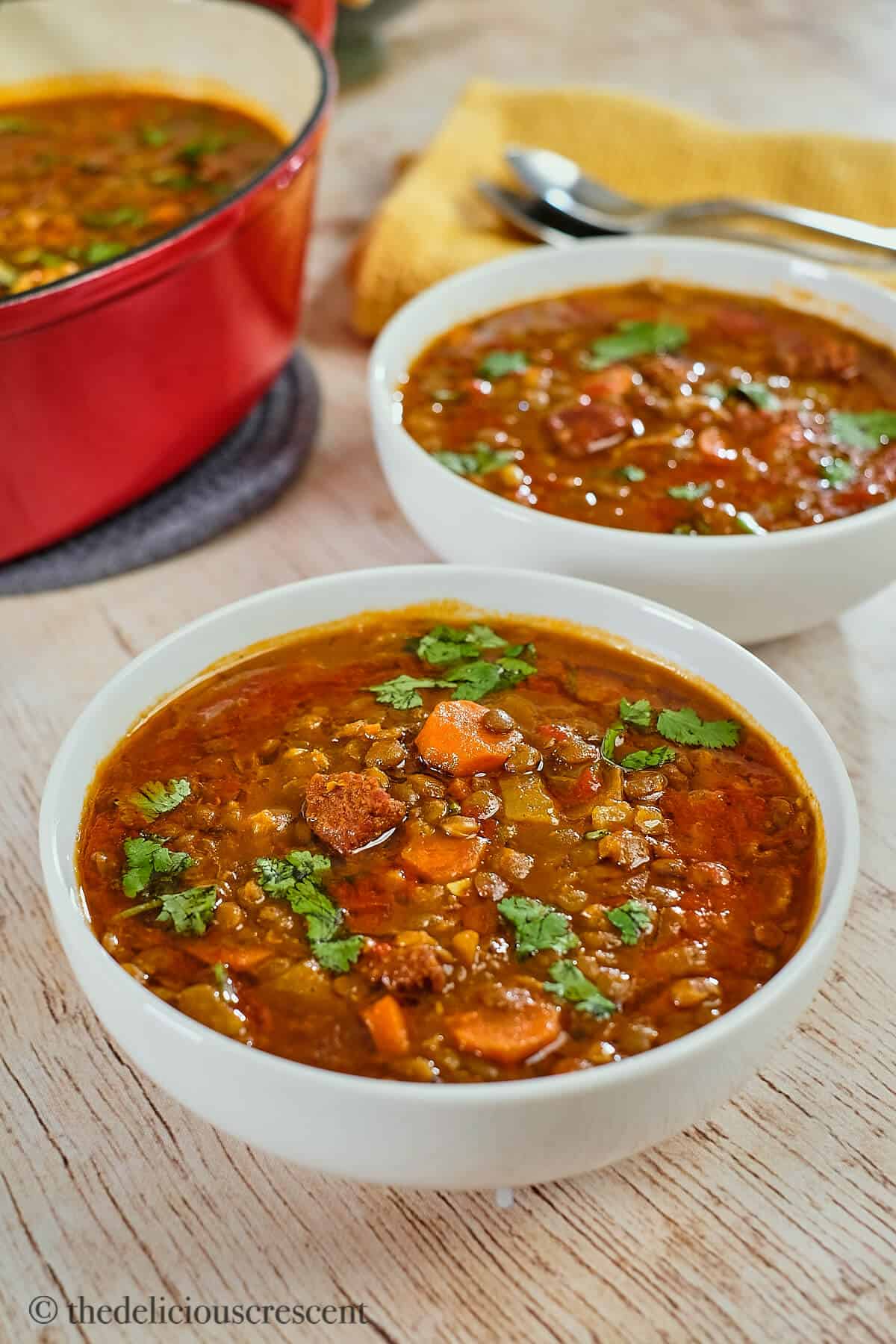 Moroccan lentil soup with sausage in white bowls.