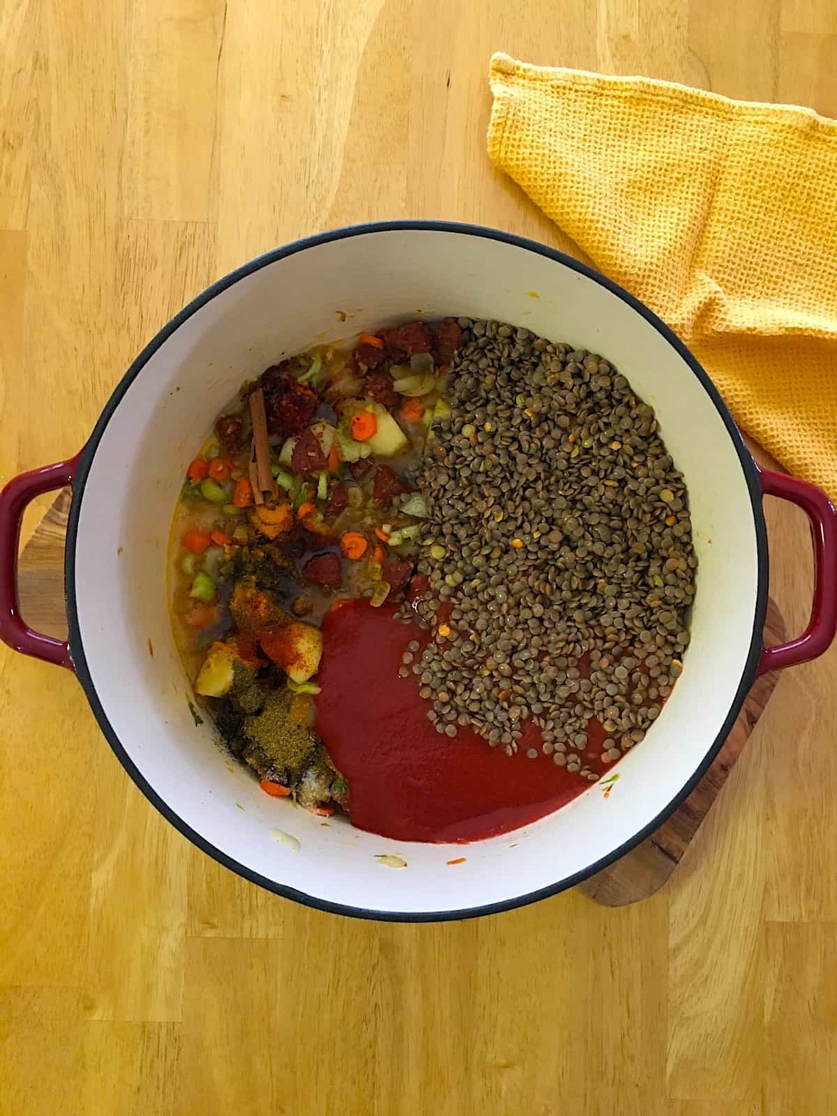 Lentils, crushed tomatoes, spices and herbs added to the cooking pot.