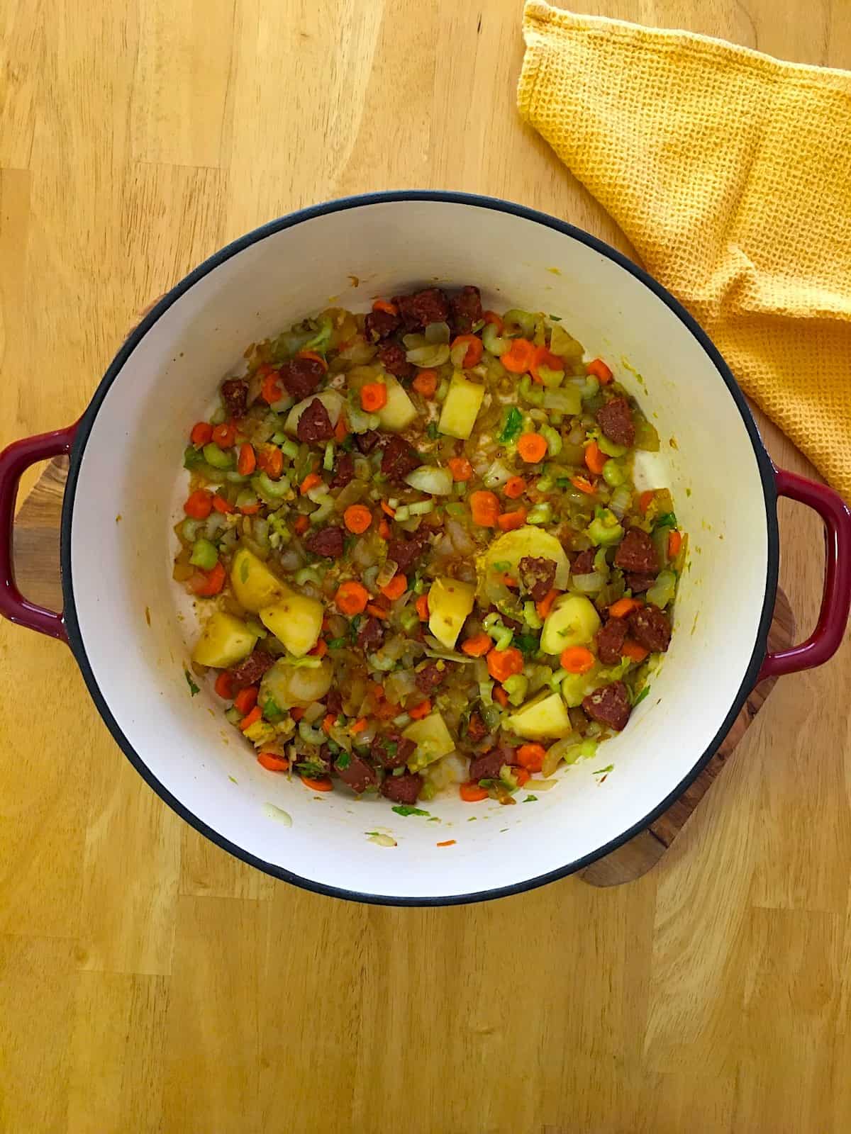 Onions, sausage and vegetables sauteed in a dutch oven.