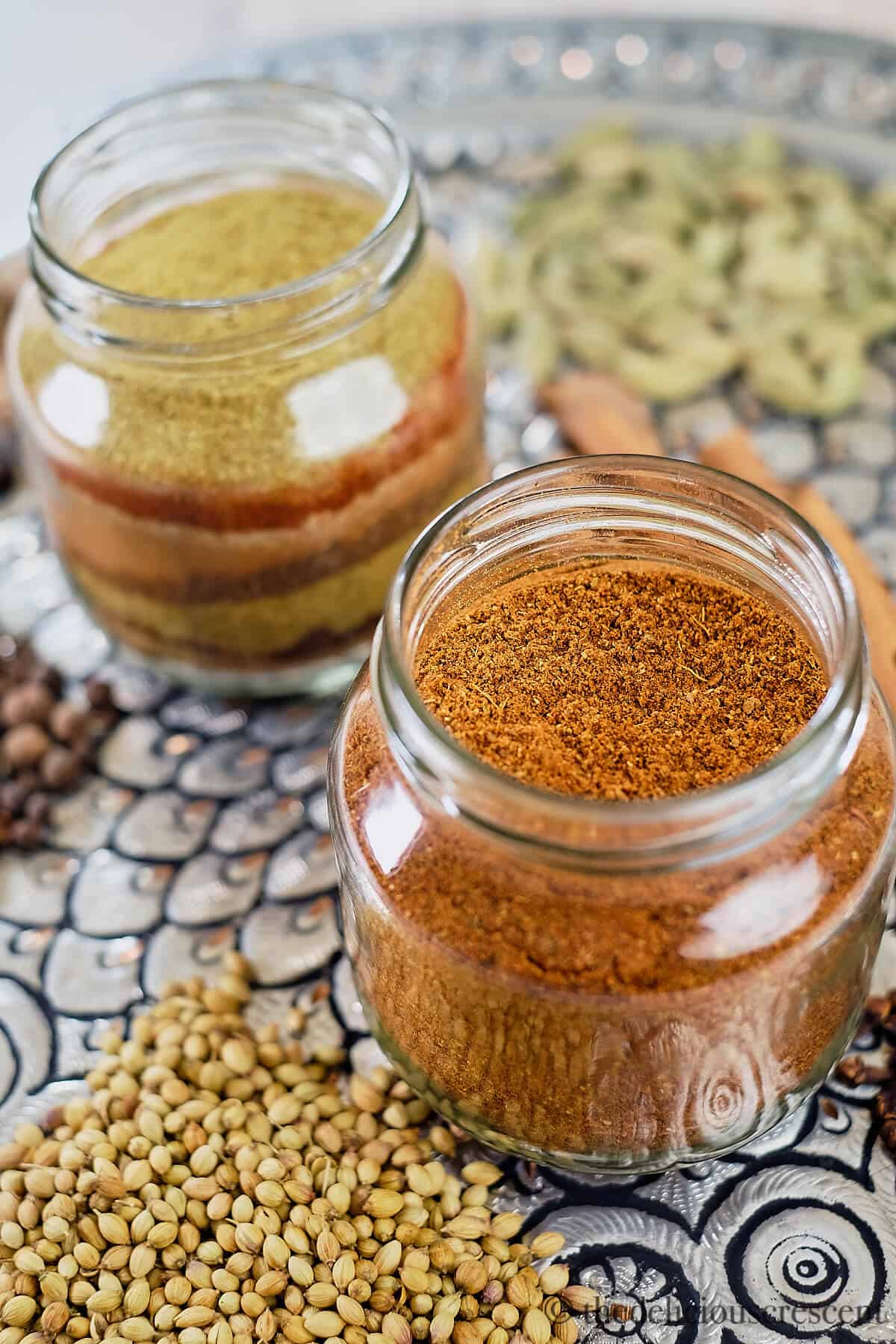 Two bottles of baharat spice blend placed on a platter.