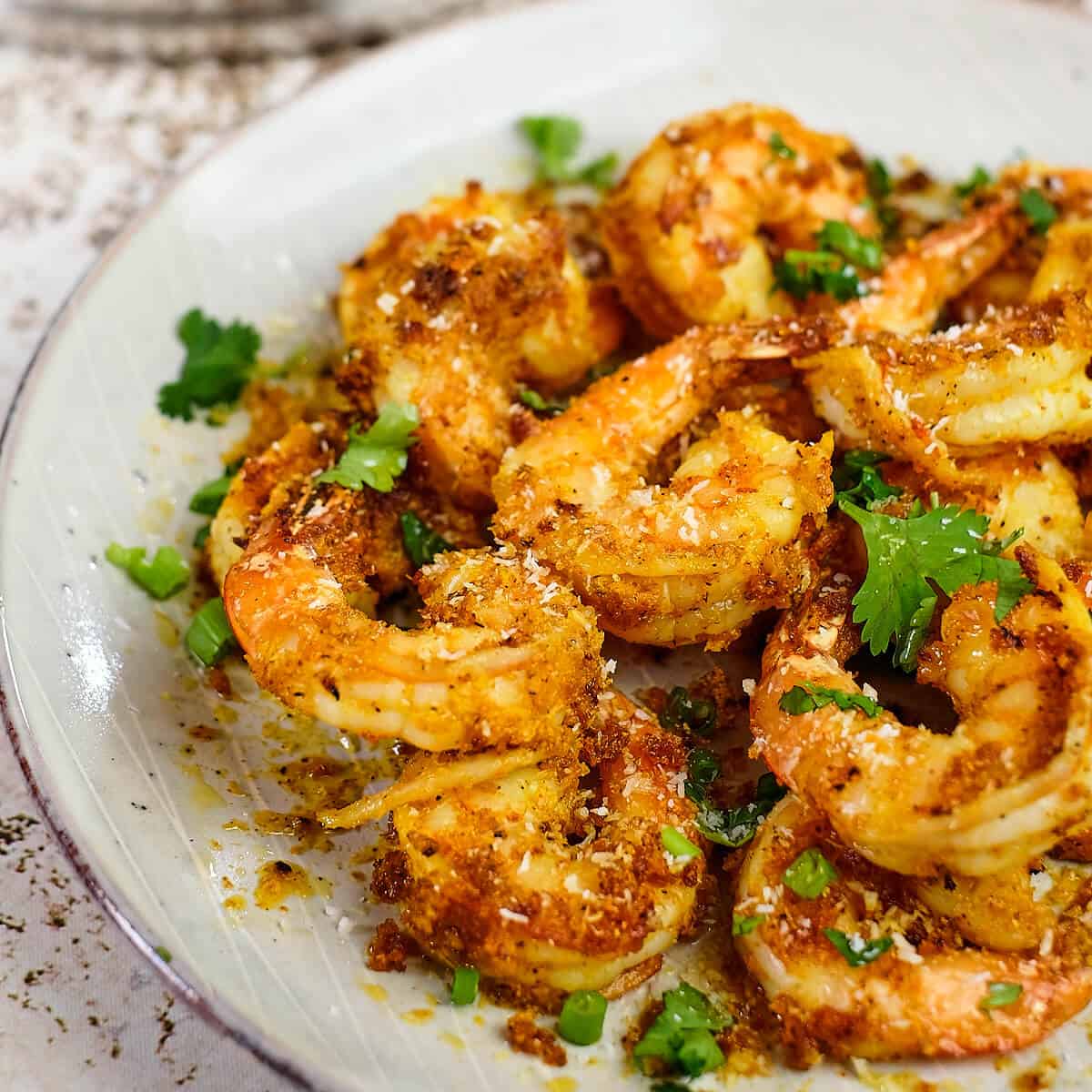 Close view of sauteed shrimp in a white plate.