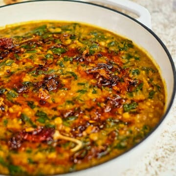 Close up view of dal palak served in a white casserole pot.