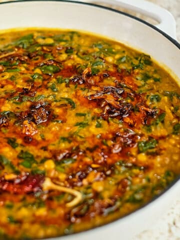Close up view of dal palak served in a white casserole pot.