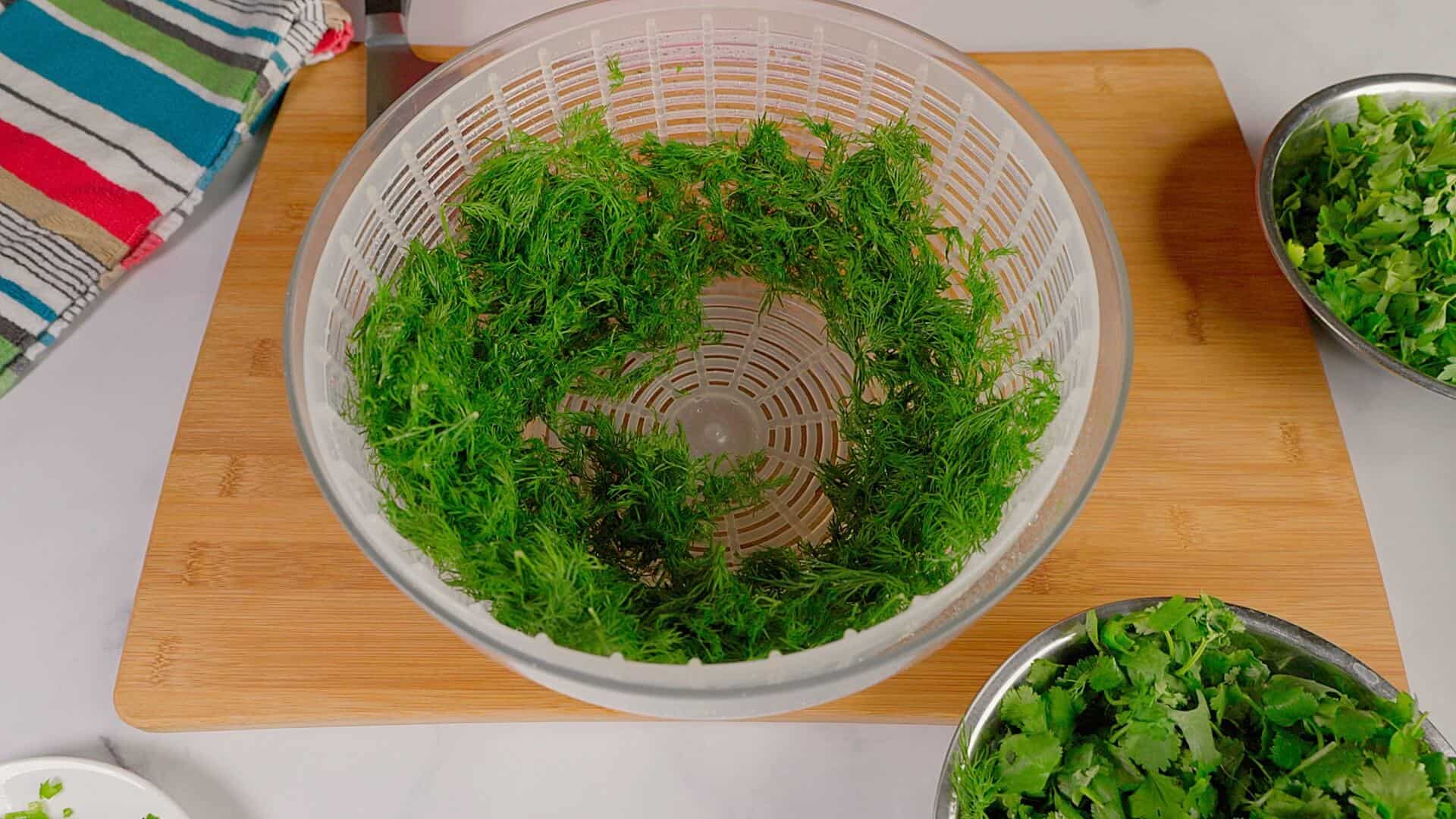 Rinsed herbs being run through a salad spinner.