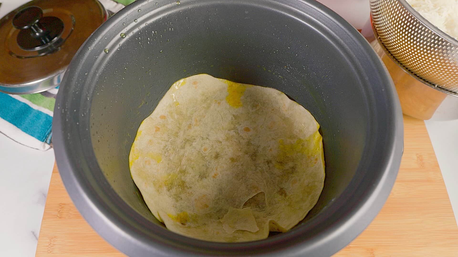 Flatbread placed in the bottom of the pot for making the tahdig.