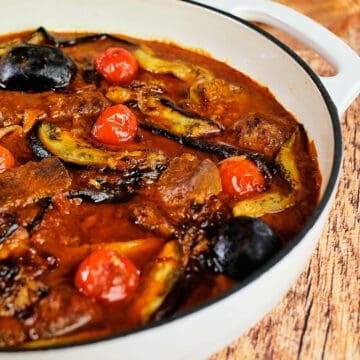 Close view of khoresh bademjan served in a white casserole dish.