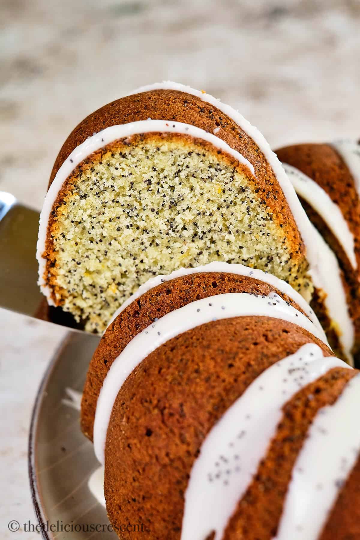 A slice of lemon poppy seed cake lifted from the plate.