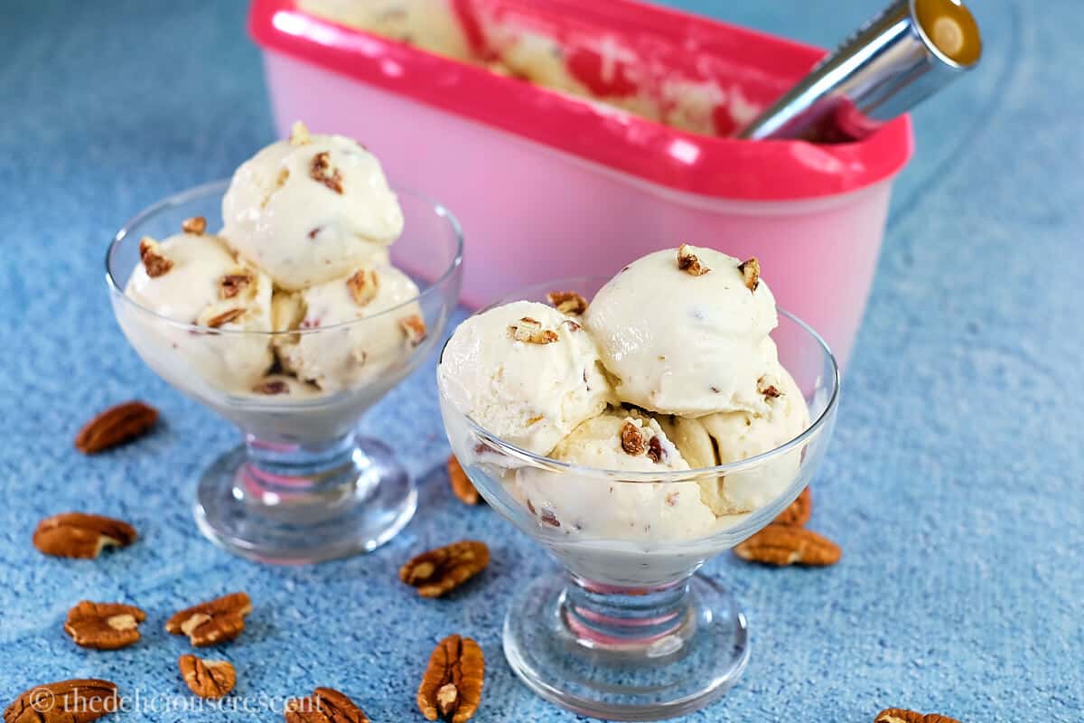 Maple ice cream in bowls with pecans scattered around.