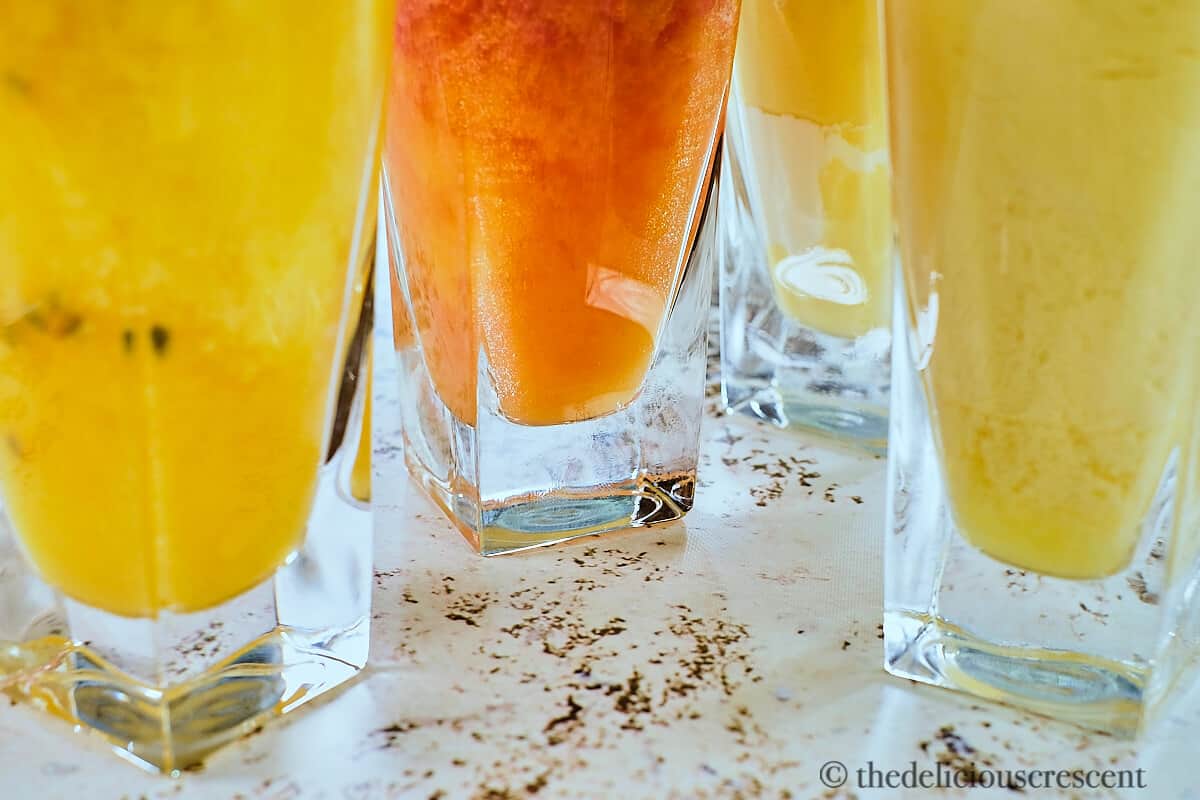 Four delectable peach smoothies in glasses.