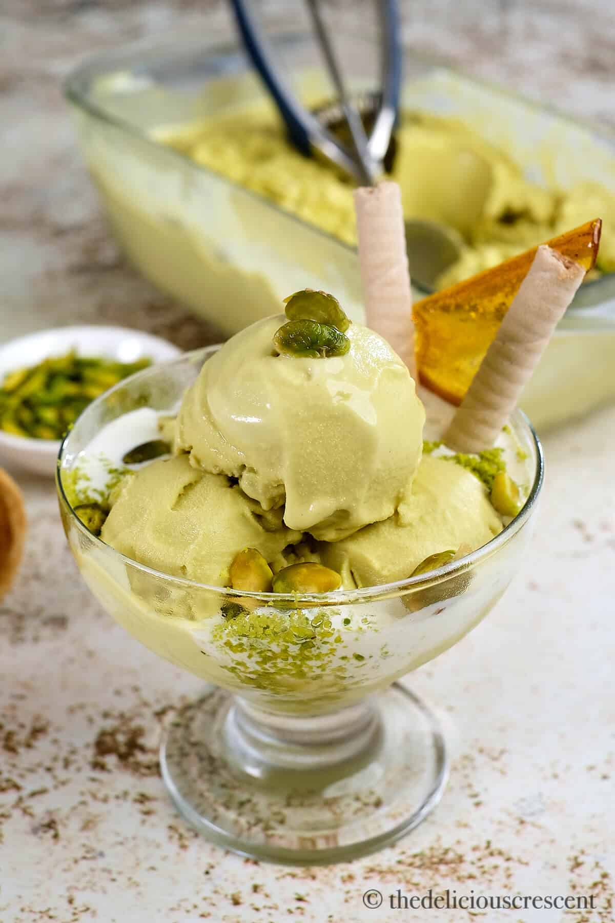 Scoops of Italian style pistachio ice cream in a glass cup.