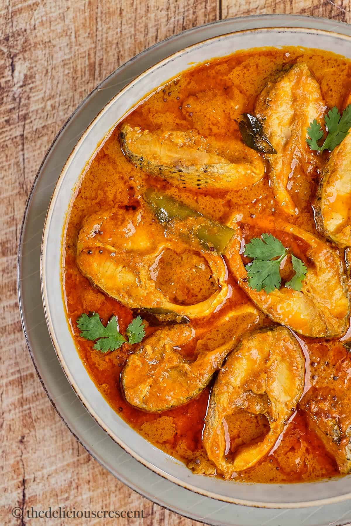 Delicious Indian fish curry served in a grey bowl.