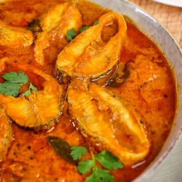 Close view of Indian fish curry with coconut based sauce in a bowl.