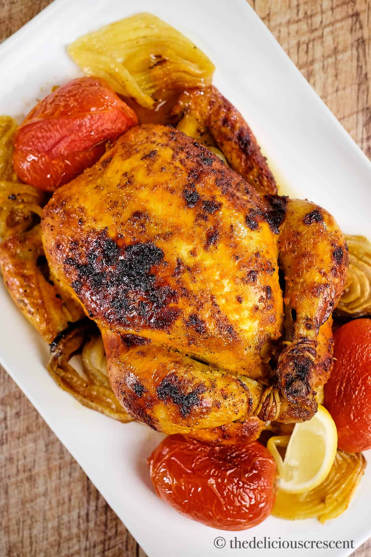 Saffron chicken served with roasted vegetables on a white plate.