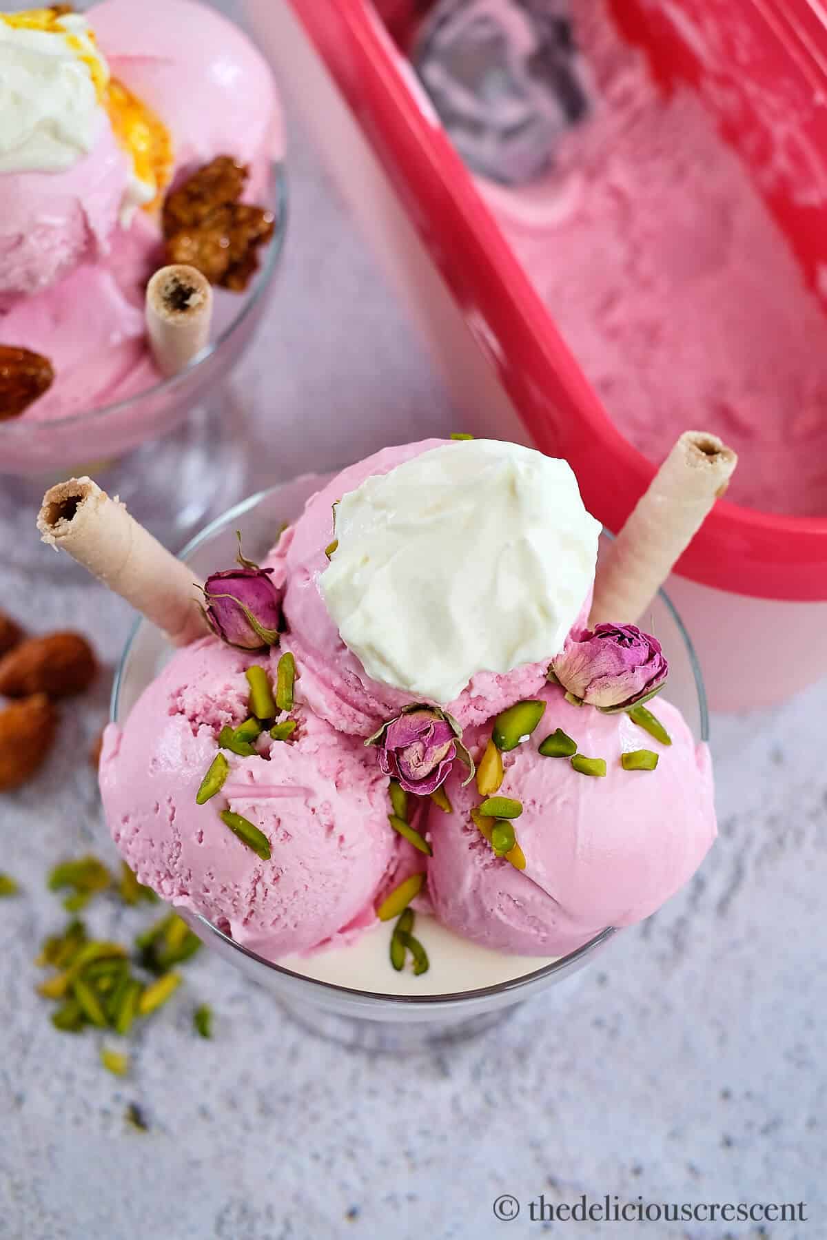 A dollop of cream and nuts over pink frozen treat.