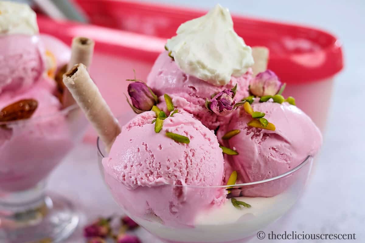 Rose ice cream served with cream and pistachios.
