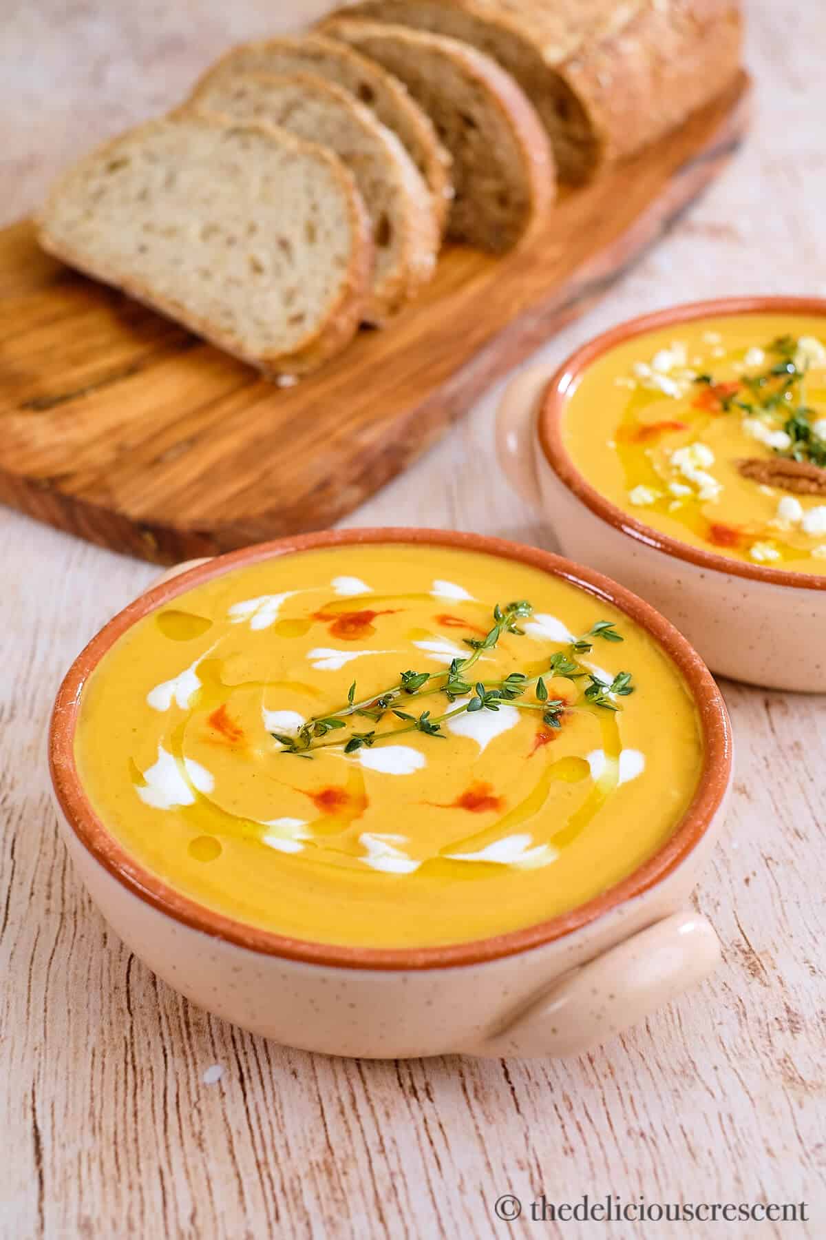 Two bowls of soup served with bread.