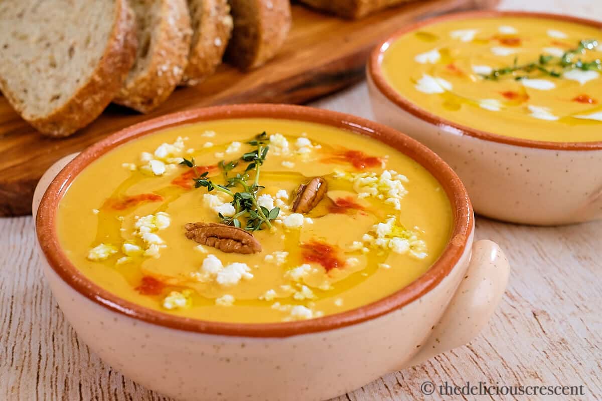 Spicy butternut squash soup served in bowls with toppings.