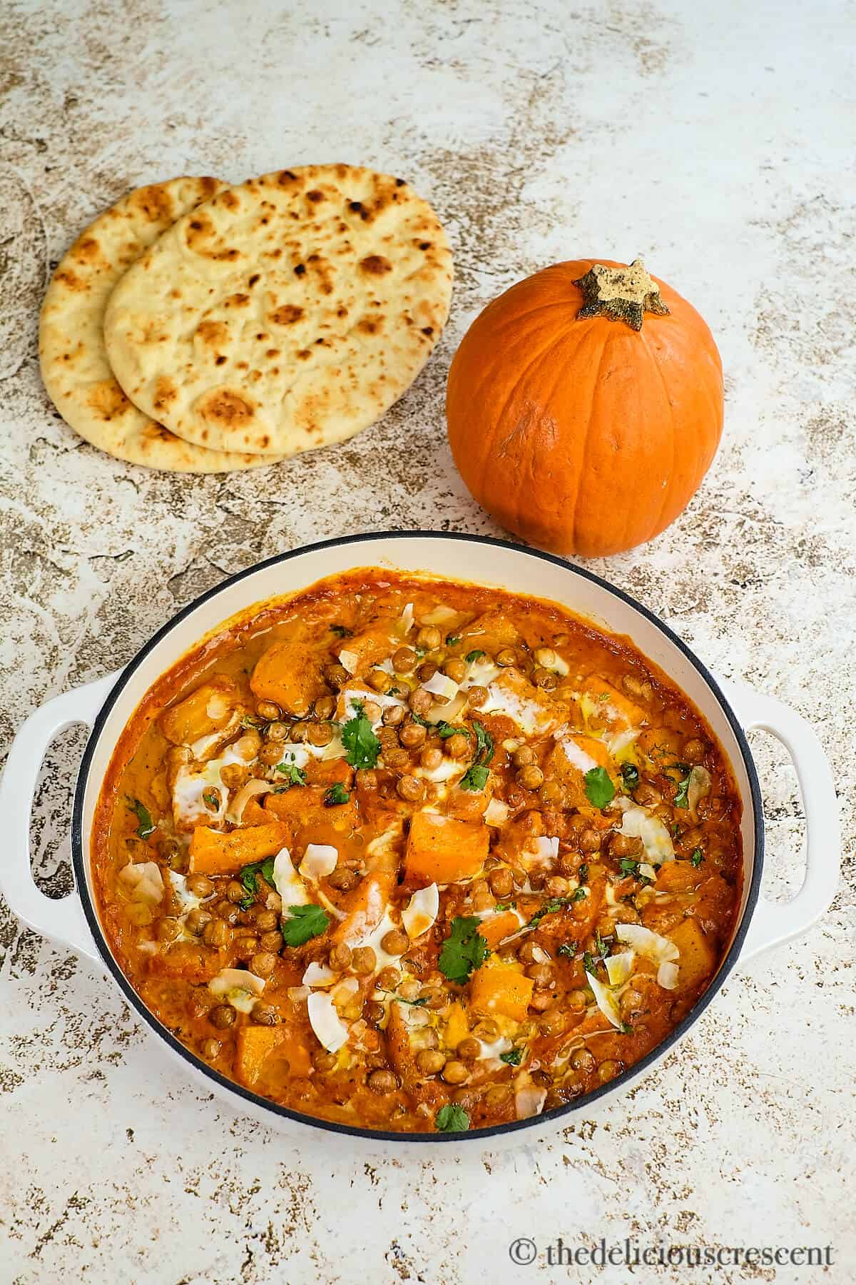 A vegetable stew with chickpeas on placed the table with naan.
