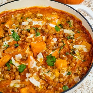 Close up view of pumpkin curry with chickpeas and coconut in a casserole dish.