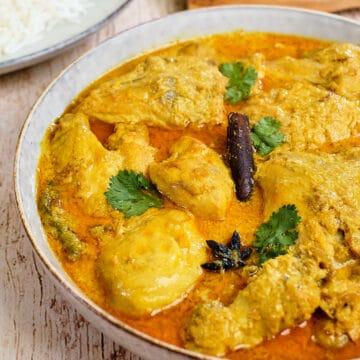 Close view of chicken curry with coconut sauce served in a grey bowl.